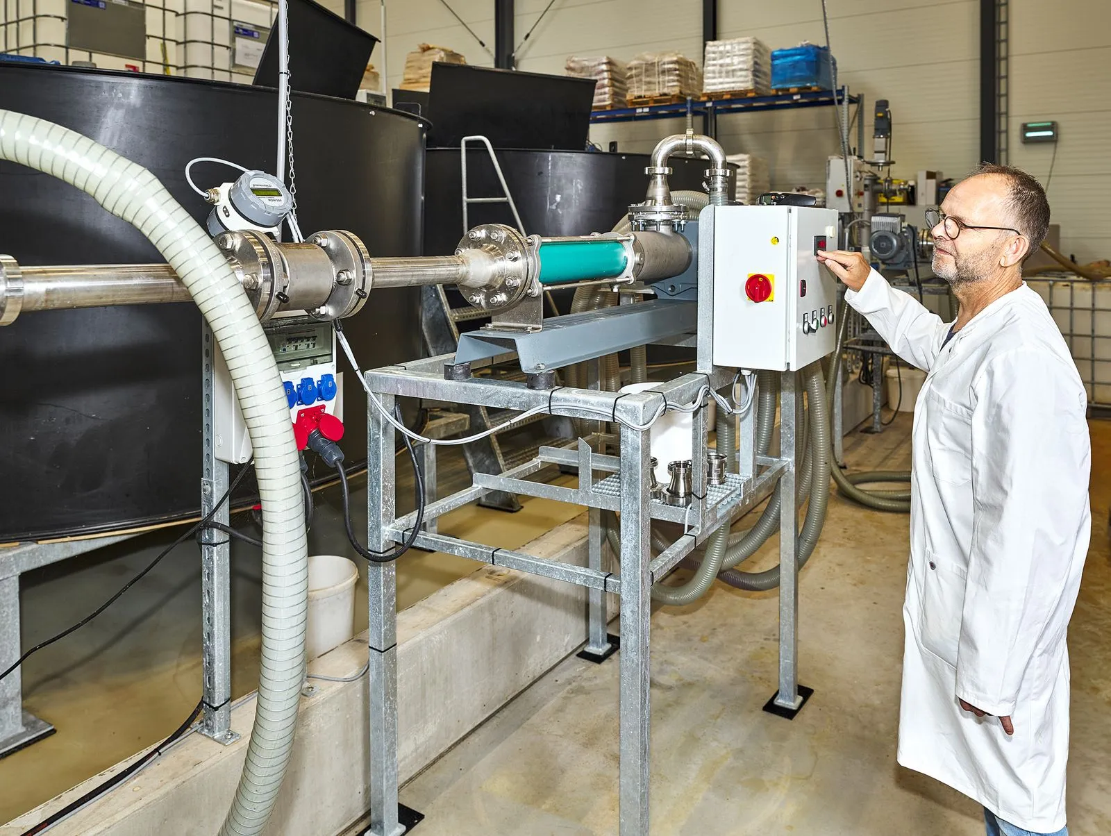 Employee in a lab coat at the control panel of a processing installation